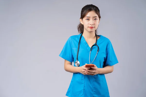 Joven Médico Asiático Con Smartphone Sobre Fondo Gris —  Fotos de Stock