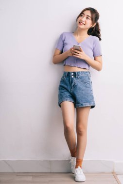 Beyaz arka planda akıllı telefon kullanan genç Asyalı kadın.