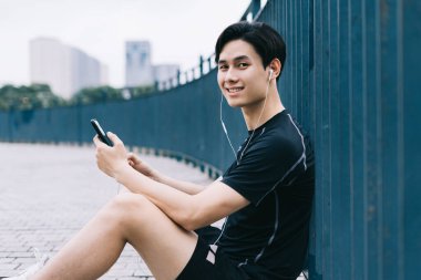 Genç Asyalı adam antrenmandan sonra dinleniyor.