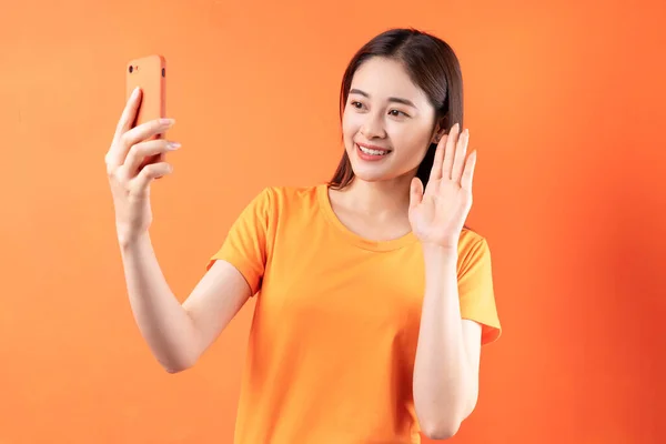 Bild Ung Asiatisk Kvinna Som Håller Smartphone Orange Bakgrund — Stockfoto