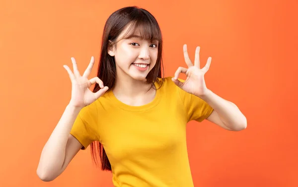 オレンジ地に黄色のTシャツを着た若いアジア人女性のイメージ — ストック写真