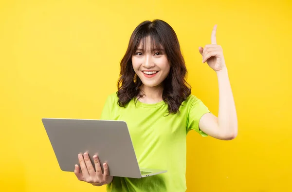 Sarı Arka Planda Dizüstü Bilgisayar Kullanan Asyalı Genç Bir Kız — Stok fotoğraf