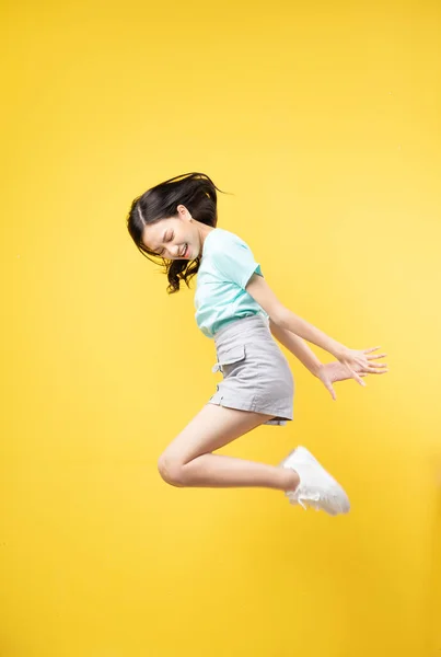 Giovane Asiatico Ragazza Jumping Giallo Baclground — Foto Stock