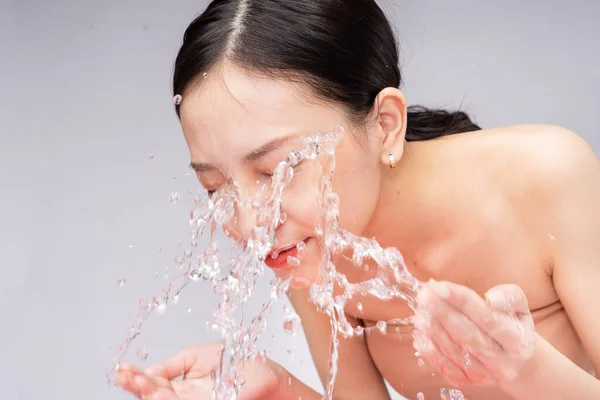 美丽的亚洲女人用纯净水洗脸 — 图库照片