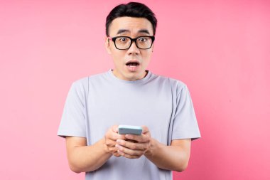 Pembe arka planda akıllı telefon kullanan Asyalı adamın portresi
