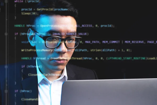 Asian man focusing on programming with lines of code running on the screen