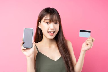 Pembe arka planda telefon kullanan güzel Asyalı genç kız.