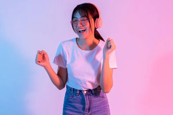 年轻的亚洲女孩戴着耳机 兴奋地听着音乐 — 图库照片