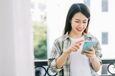 Evde akıllı telefon kullanan Asyalı genç bir kadının portresi