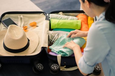 Asyalı kadın seyahat hazırlıkları için bavullarını hazırlıyor.
