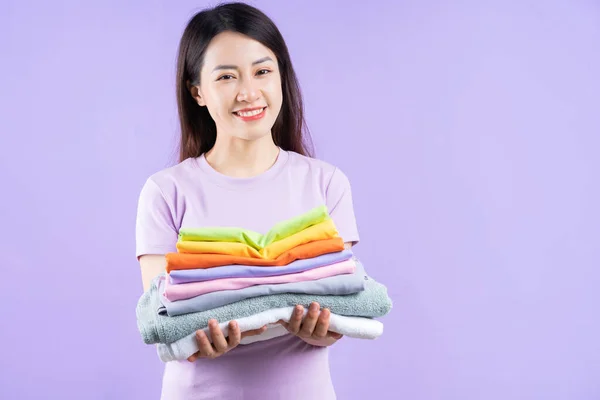 Молода Азіатка Тримає Фіолетовому Фоні Купу Одягу — стокове фото