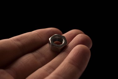 screw-nut in hands on a black background