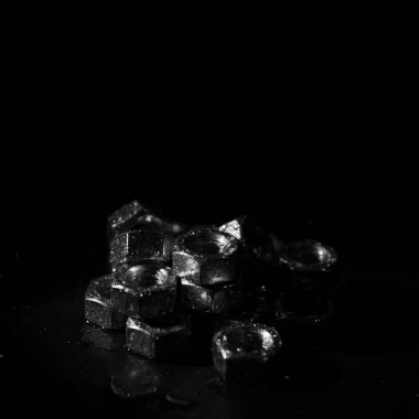 screw-nuts with water drops on a dark surface
