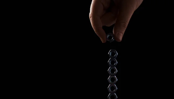 screw-nuts in hands on a black background