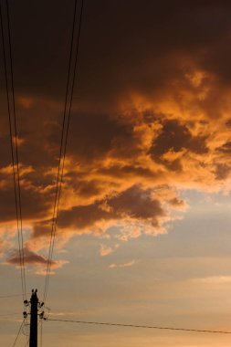 Gün batımında bulutlar ve elektrik hattı sütunu