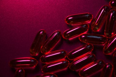 Kırmızı ışığın altındaki karanlık bir yüzeyde yarı saydam kapsüller