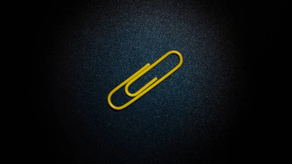 Clipe Papel Amarelo Deitado Uma Superfície Metal Azul Escuro — Fotografia de Stock