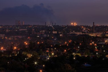 Dağlık bölgede fenerleri olan şehir. Gün batımı veya şafak vakti gökyüzü olan.