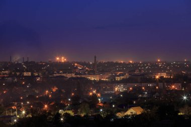 Dağlık bölgede fenerleri olan şehir. Gün batımı veya şafak vakti gökyüzü olan.