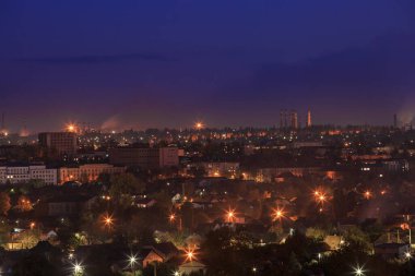Dağlık bölgede fenerleri olan şehir. Gün batımı veya şafak vakti gökyüzü olan.