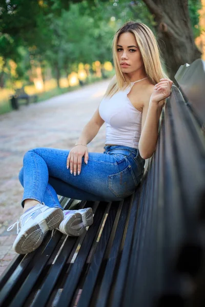 Una Joven Rubia Sentada Con Las Piernas Banco Parque —  Fotos de Stock