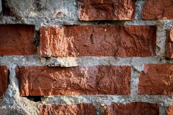 The brick in the wall is crumbling from time, close-up