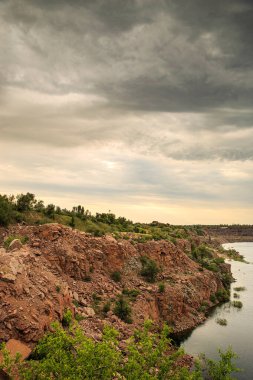 Bulutlu bir günde eski bir kırmızı granit ocağının kıyıları suyla doldu..