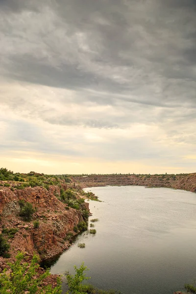 Bulutlu bir günde eski bir kırmızı granit ocağının kıyıları suyla doldu..