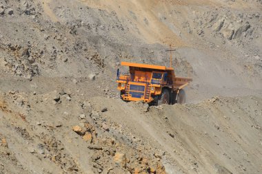 Güneşli bir günde yoldaki büyük sarı maden damperli kamyon. Bir maden ocağında kaya kütlesi taşımak için büyük ölçekli ekipman..
