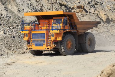 Güneşli bir günde yoldaki büyük sarı maden damperli kamyon. Bir maden ocağında kaya kütlesi taşımak için büyük ölçekli ekipman..