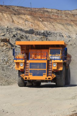 Güneşli bir günde yoldaki büyük sarı maden damperli kamyon. Bir maden ocağında kaya kütlesi taşımak için büyük ölçekli ekipman..
