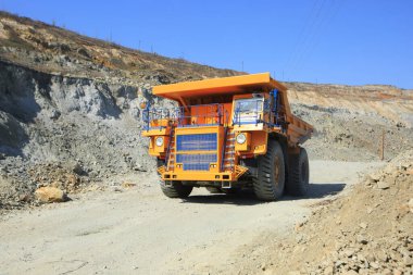 Güneşli bir günde yoldaki büyük sarı maden damperli kamyon. Bir maden ocağında kaya kütlesi taşımak için büyük ölçekli ekipman..