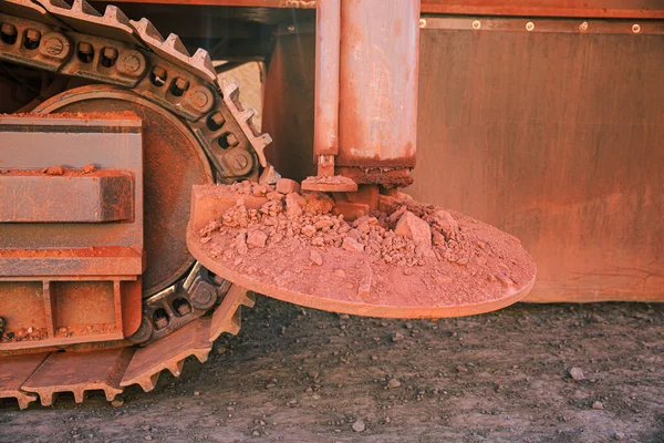 Hydraulic supports for a crawler crane stained with red rocks on the ground