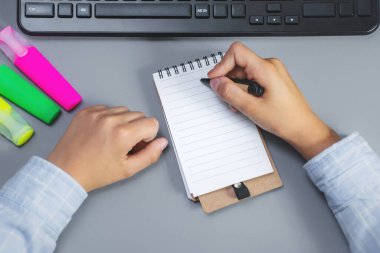 Çocuk bir masaüstü arka planına bir defter yazar.