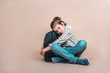 Bej arka planda sırt çantası olan bir çocuk. Okula geri dön..