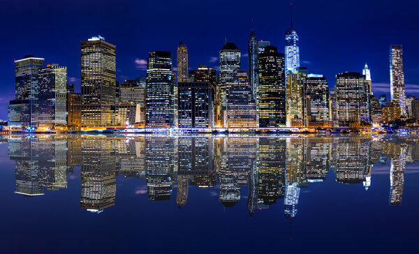 Panoramic night view of New York City with reflection in water