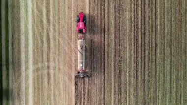 Vogelperspektive auf einen Traktor, der im Fruehling das Feld umgraebt.