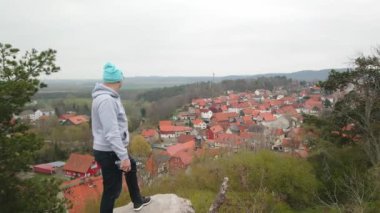 Küçük bir Alman kasabasının çatılarını gören bir adamın yanından uçarak geç.