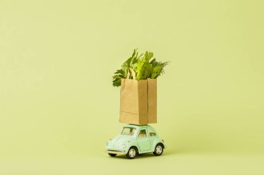 Irkutsk, Rusya - 3 Ekim 2020: açık yeşil retro oyuncak araba içinde taze yeşil salata bulunan kağıt alışveriş torbaları taşıyor. Eko-Gıda teslimat konsepti, vejetaryenlik. Bağış.