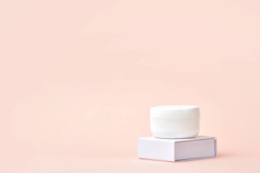 Beyaz kozmetik krem kapaklı. Yan görüş. Açık pembe arka planda kadın hijyenik cilt ürünleri. Güzellik endüstrisi konsepti. Boşluğu kopyala.