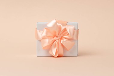 Sevgililer Günü geçmişi. Sevgililer Günü konsepti. Mutlu Kadınlar Günü şablon tasarımı. Dekoratif beyaz hediye kutusu. Pastel mercan arka planında şeftali yaylı. Merkezde yakın plan nesne.