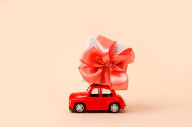 Yeni yıl, pembe arka planda çatıda hediyesi olan küçük kırmızı oyuncak araba. Noel, Sevgililer Günü, Dünya Kadınlar Günü hediyeleri. Satış konsepti.