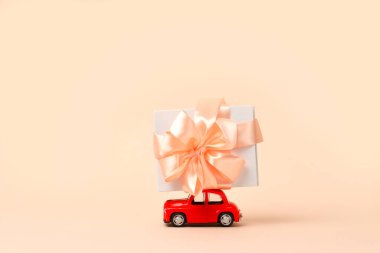 Pembe arka planda çatıda hediyesi olan küçük kırmızı bir oyuncak araba. Yeni yıl, Noel, Sevgililer Günü, Dünya Kadınlar Günü hediyeleri. Satış konsepti.