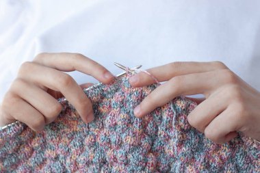 Beyaz arka planda iki el örgü şişi ve yakın plan örgü tutuyor. El yapımı konsepti, ev yapımı, hobiler.