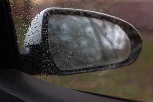 Photo from the car through the glass you can see the car mirror, raindrops on the glass, selective focus — Stock Photo, Image