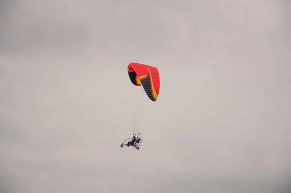 Extreme sport. red paraglider flies in the cloudy sky.