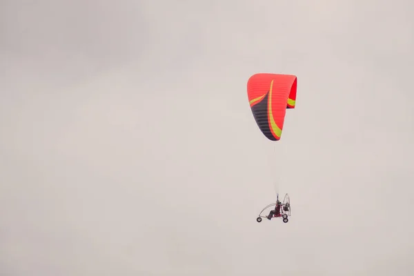 極端なスポーツだ 赤いパラグライダーが曇った空を飛ぶ — ストック写真