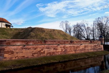 Kırmızı tuğladan oluşan büyük toprak duvar güçlü bir savunmadır. Etrafı suyla çevrili koruyucu bir hendekle çevrilidir. Avrupa 'nın merkezinde eski ortaçağ kaleleri. Siren bulutlu mavi gökyüzü.