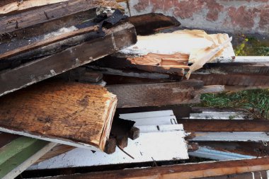 Yerde eski bir duvarın arkasında duran bir yığın tahta.