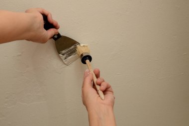 Kadın sıvacı macunla duvarı onarıyor. Bir fırçayla, usta aletten macun toplar. Yakın plan, kopyalama alanı.
